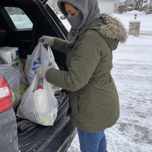 Customer unloading groceries in snow wearing gray fleece hood
