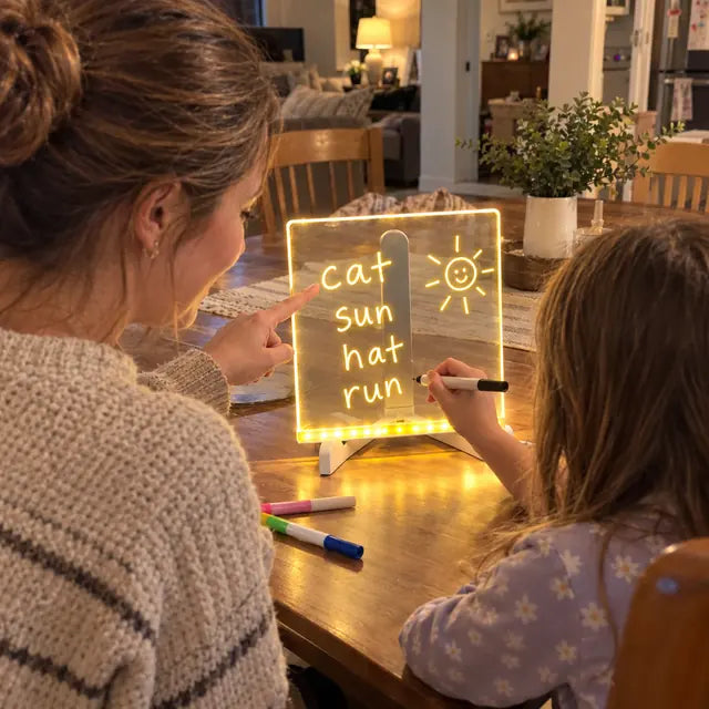 Parent helping a child practice words on a glowing acrylic LED board
