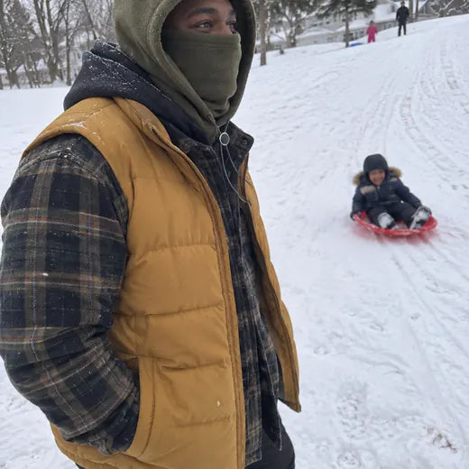 Parent sledding with child while wearing olive fleece hood